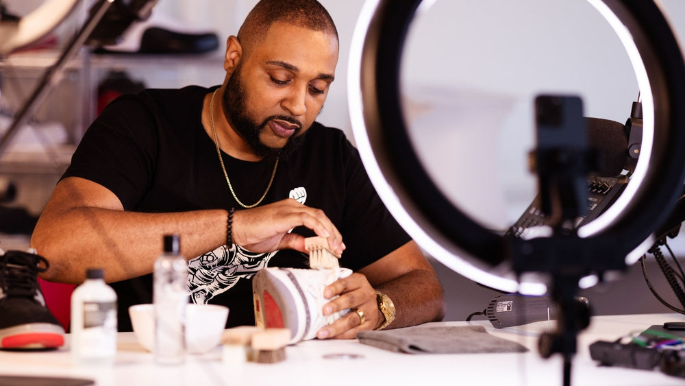 Richard Brown, founder of Proof Culture, cleaning sneakers at Proof Culture with sneaker care tools and ring light.